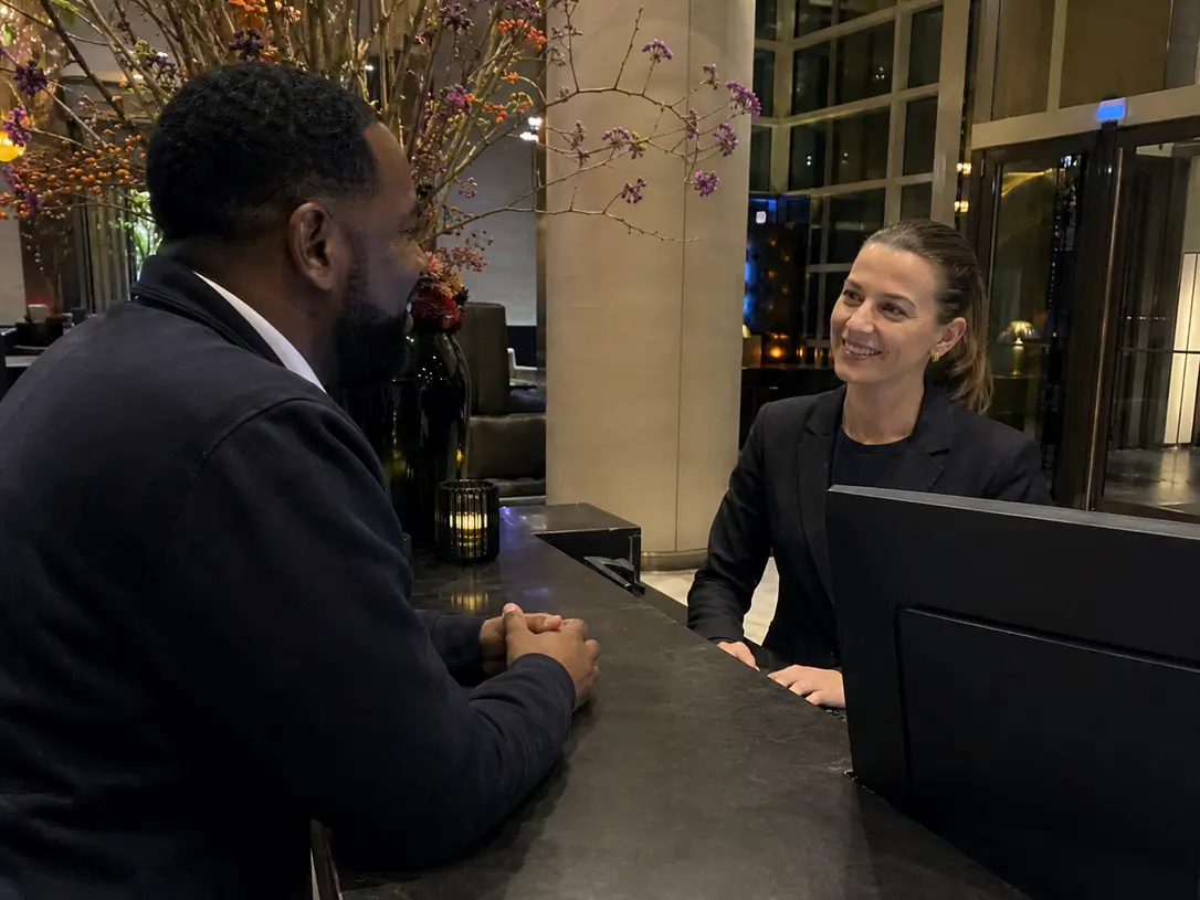 Medewerker verwelkomt een bezoeker met een glimlach aan de balie van Adams Security