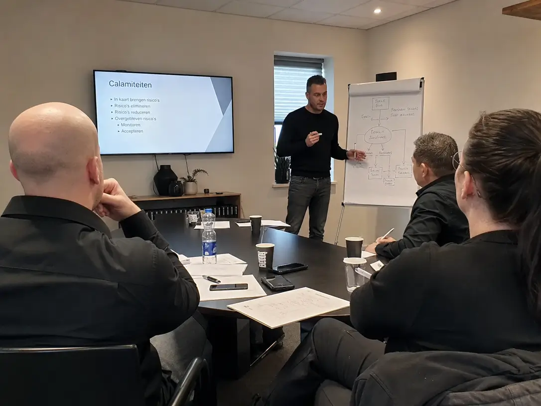 Beveiliger geeft uitleg aan een team voor een whiteboard met calamiteitenplan