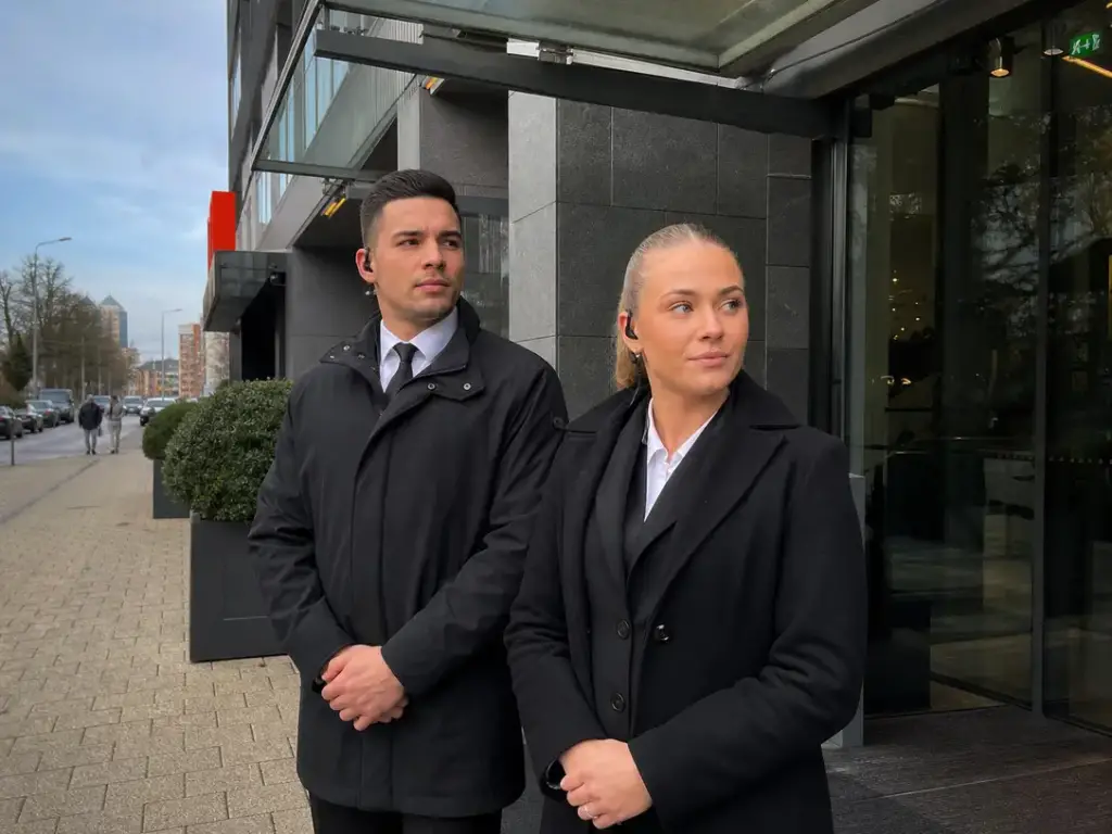 Man en vrouw beveiliger van Adams Security met oortelefoon en zwart jack